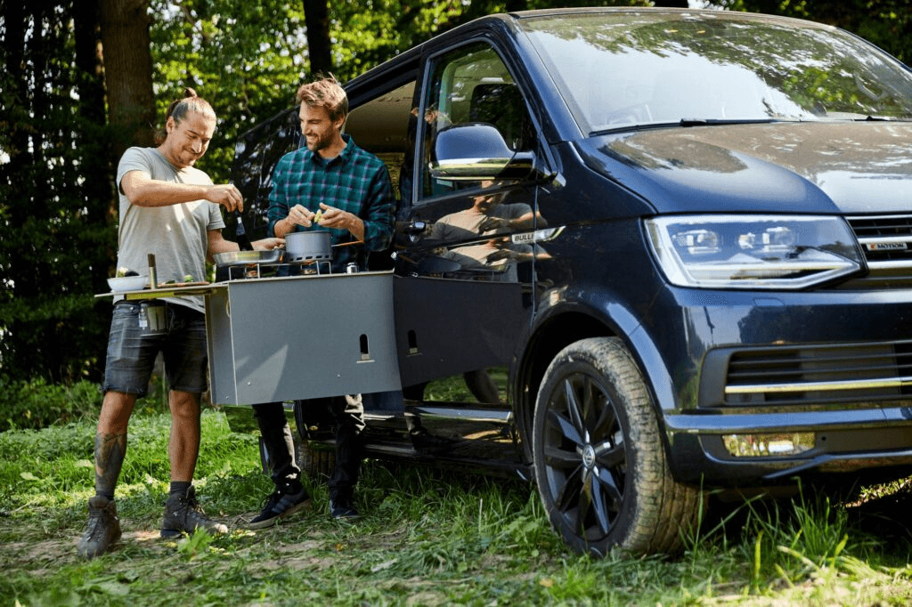 Zwei Personen mit Camptools-Ausrüstung am Auto
